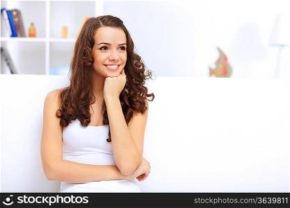 Young pretty woman in white at home sitting on the sofa