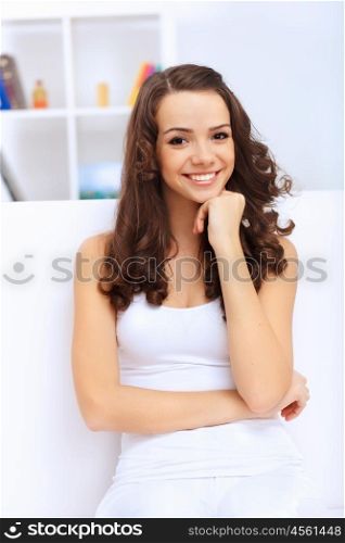 Young pretty woman in white at home sitting on the sofa