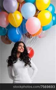 Young pretty woman in white dress with color balloons on white background with copy space for text. Woman with color balloons