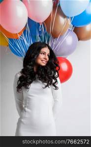 Young pretty woman in white dress with many color balloons on white background. Woman with color balloons