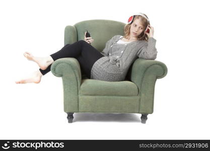 young pretty woman listening to music in armchair against white background