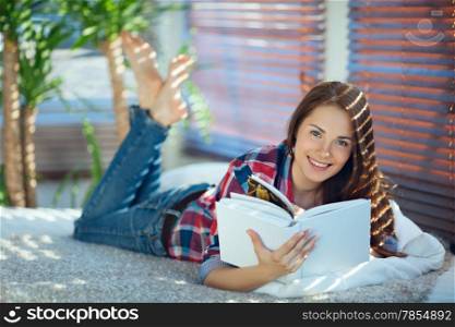 Young pretty woman lying on her stomach and reading