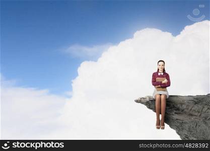 Young pretty woman on rock top with book in hands. Woman with book