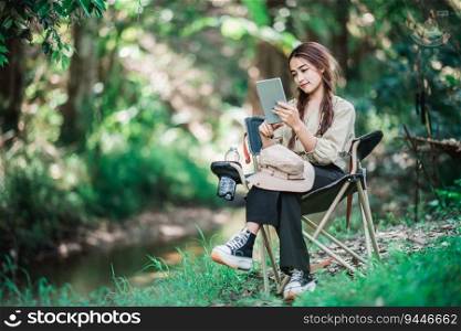 Young pretty woman sitting in chair and use tablet video call while c&ing in nature park, copy space
