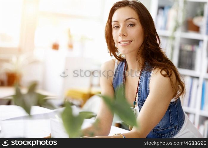 Young pretty woman smiling at her desk in office. Young pretty woman smiling at her desk in her office