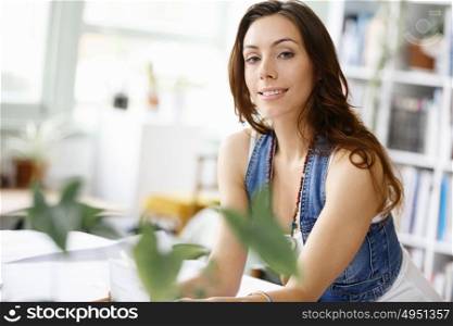 Young pretty woman smiling at her desk in office. Young pretty woman smiling at her desk in her office