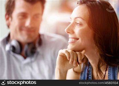 Young pretty woman smiling with man on background. Young pretty woman smiling in office with her colleague on background