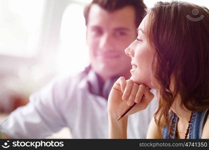 Young pretty woman smiling with man on background. Young pretty woman smiling in office with her colleague on background