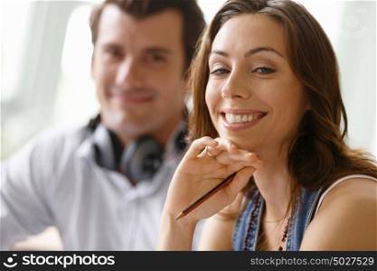 Young pretty woman smiling with man on background. Young pretty woman smiling in office with her colleague on background