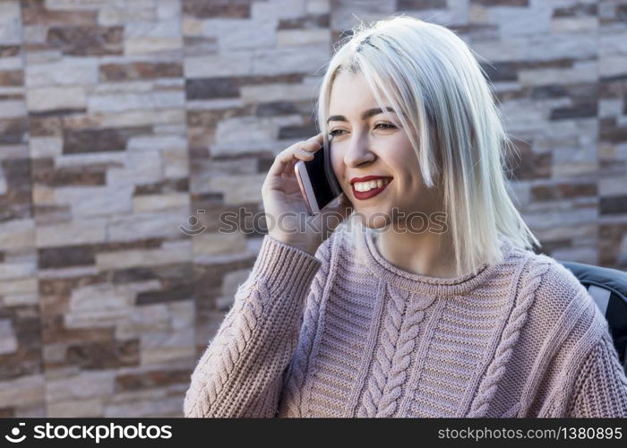 Young pretty woman talking on cellphone while sitting on sofa on terrace