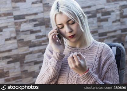 Young pretty woman talking on cellphone while sitting on sofa on terrace