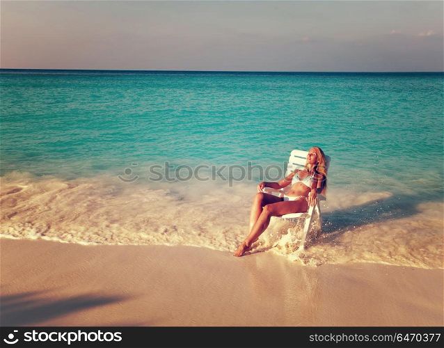 Young pretty woman tans in beach chair,with a retro effect