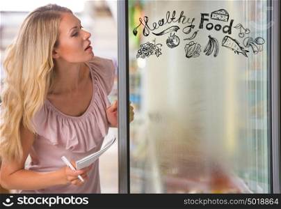 Young pretty woman thinking of healthy food while shopping at grocery store closeup portrait and sketches overhead