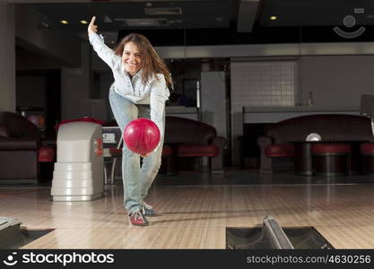 Young pretty woman throwing a bowling ball. At bowling club