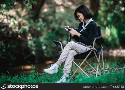 Young pretty woman use digital camera taking a photo beautiful nature while camping in forest with happiness, copy space