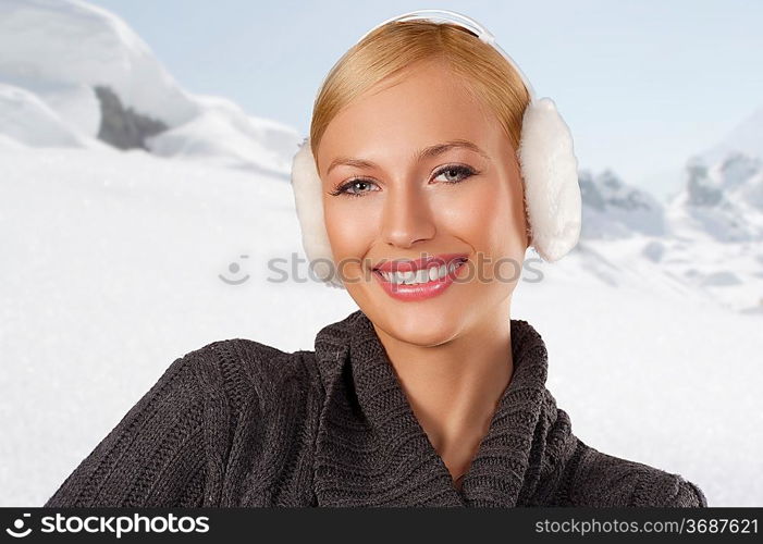 young pretty woman wearing white earmuffs and gray wool sweater be ready to go out in a cold winter day smiling against white background