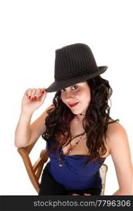 Young pretty woman with a gray hat and long black curly hair sitting ona chair, looking smiling into the camera, for white background.