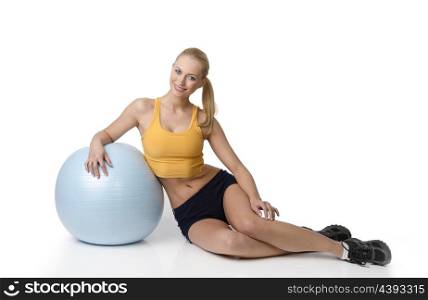 young pretty woman with fitness dress sitting on white and looking in camera