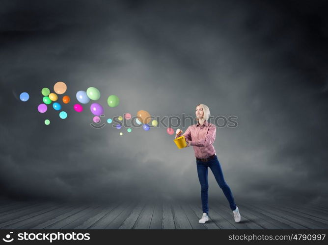 Young pretty woman with yellow bucket in hands. Girl splashing balloons from bucket