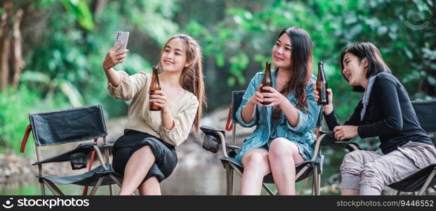 Young pretty women holding beers bottle sitting on c&ing chair in stream and use smartphone selfie with happiness