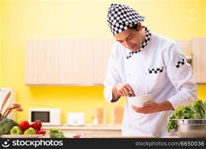 Young professional cook preparing salad at home