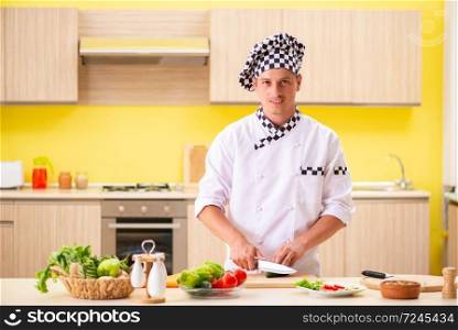 Young professional cook preparing salad at kitchen