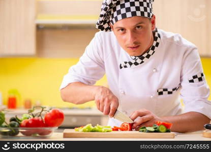 Young professional cook preparing salad at kitchen