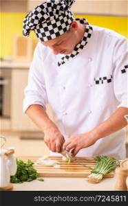 Young professional cook preparing salad at kitchen