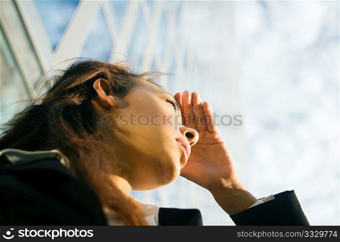 young professional woman looking far away in front of a modern office building, presumably at new career options