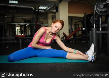 young red haired girl doing stretching in gym