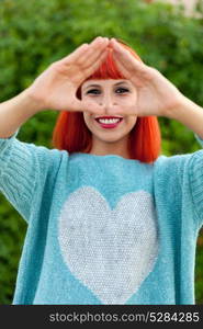 Young red haired woman doing a triangle with her hands.