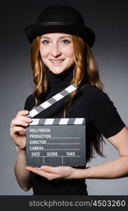 Young redhead girl in hat with movie board against grey background