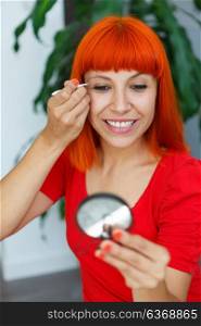 Young redhead lady using tweezers at home