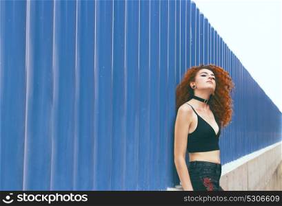 Young redhead woman against blue walls
