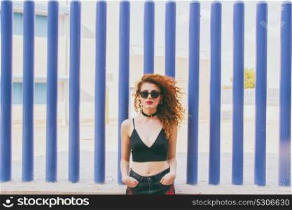 Young redhead woman against blue walls