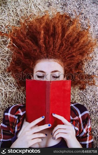 Young redhead woman covering by a book