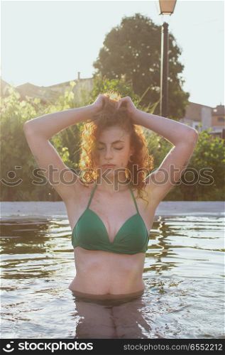 young redhead woman enjoying a summer day in a natural pool