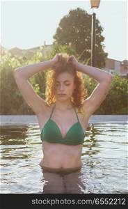 young redhead woman enjoying a summer day in a natural pool