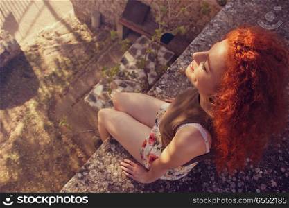 Young redhead woman enjoying the sun at sunset