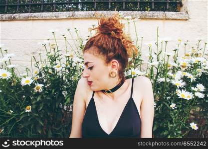 Young redhead woman surrounded by daisies
