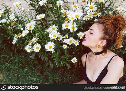 Young redhead woman surrounded by daisies