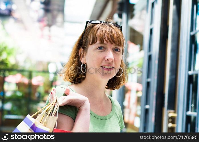 Young redhead woman with shopping bags in the city. Shopping and lifestyle concept.