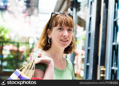 Young redhead woman with shopping bags in the city. Shopping and lifestyle concept.