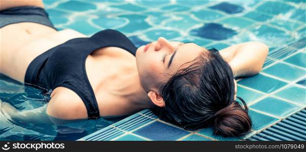 Young relaxed woman at swimming pool in summer in luxury beach resort. Travel and lifestyle.