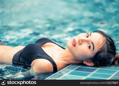 Young relaxed woman at swimming pool in summer in luxury beach resort. Travel and lifestyle.. Woman at swimming pool in summer in luxury resort.
