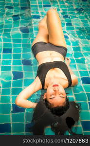 Young relaxed woman at swimming pool in summer in luxury beach resort. Travel and lifestyle.