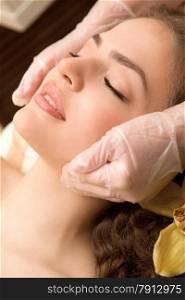 Young relaxing beautiful woman having facial lymphatic massage