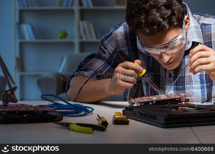 Young repair technician soldering electrical parts on motherboard. Young repair technician soldering electrical parts on motherboar