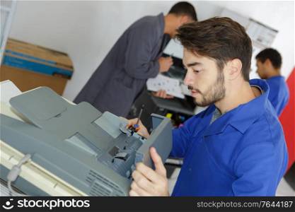 young repairer fixing photocopier