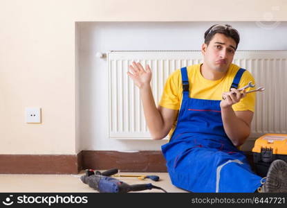 Young repairman contractor repairing heating panel